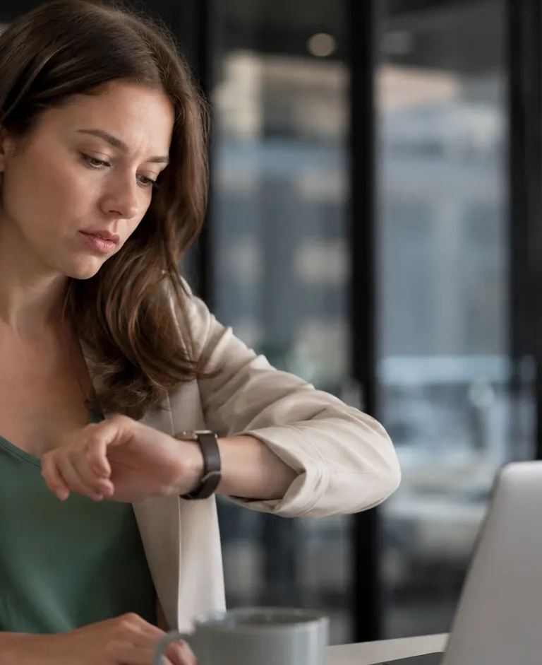 Employee checking the time at a desk in a modern office, illustrating workplace scheduling and time management on Election Day.