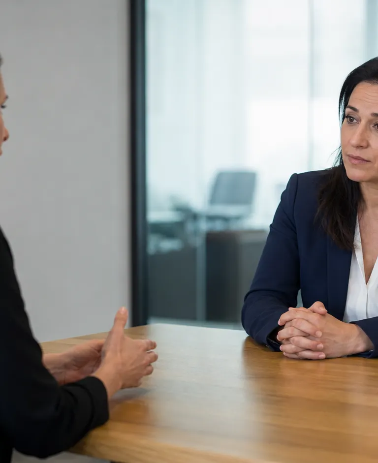 Two professionals discuss an employment matter across a conference table in a modern office.